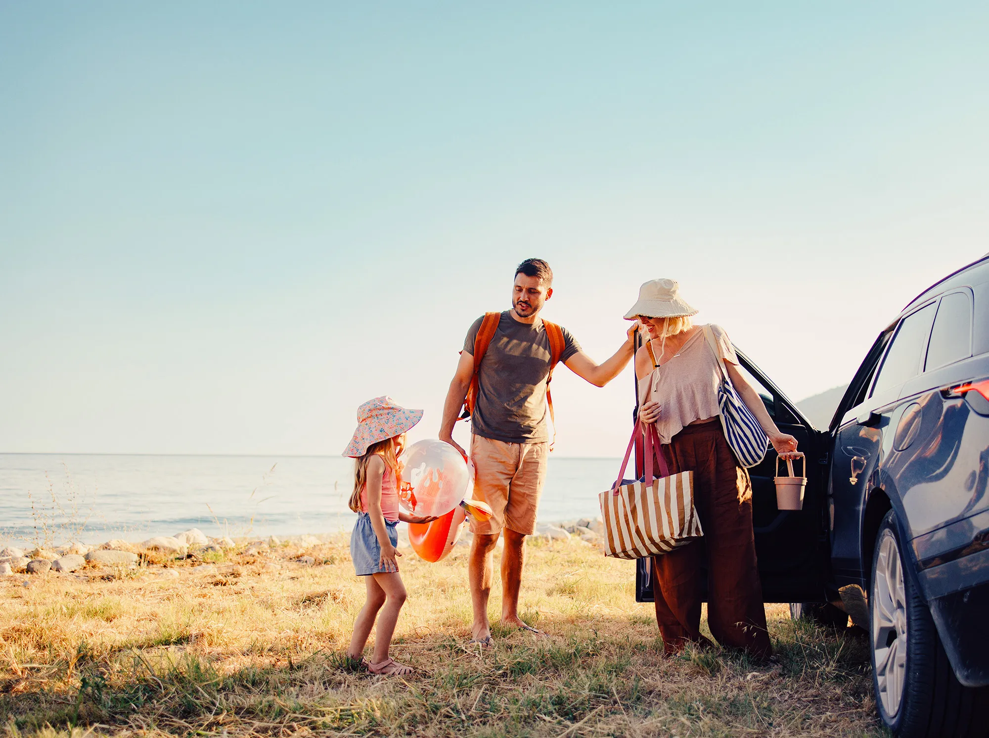 family by the car at the beach
