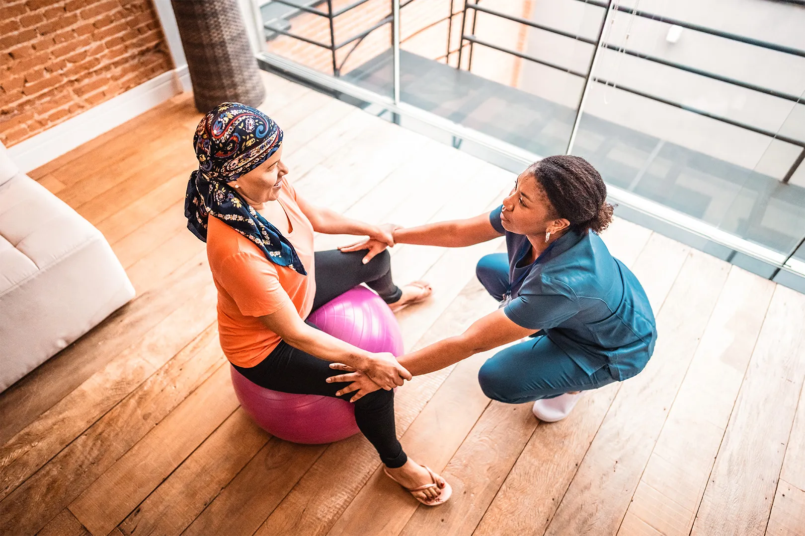 physiotherapist helping patient on medicine ball