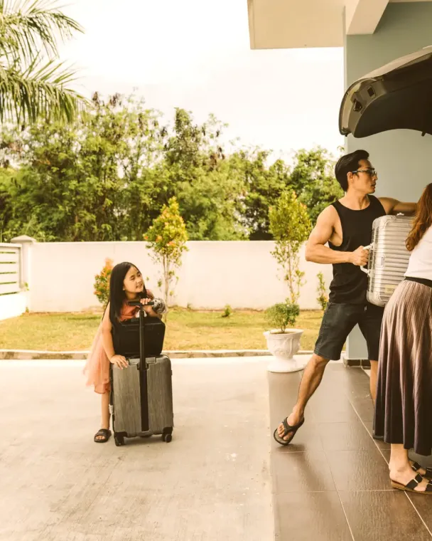 Family packing suitcases into a car