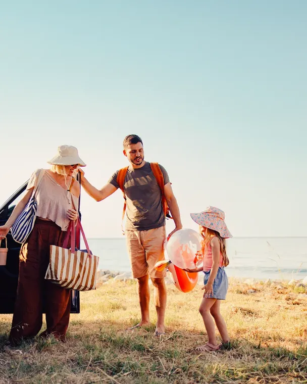 family by the car at the beach